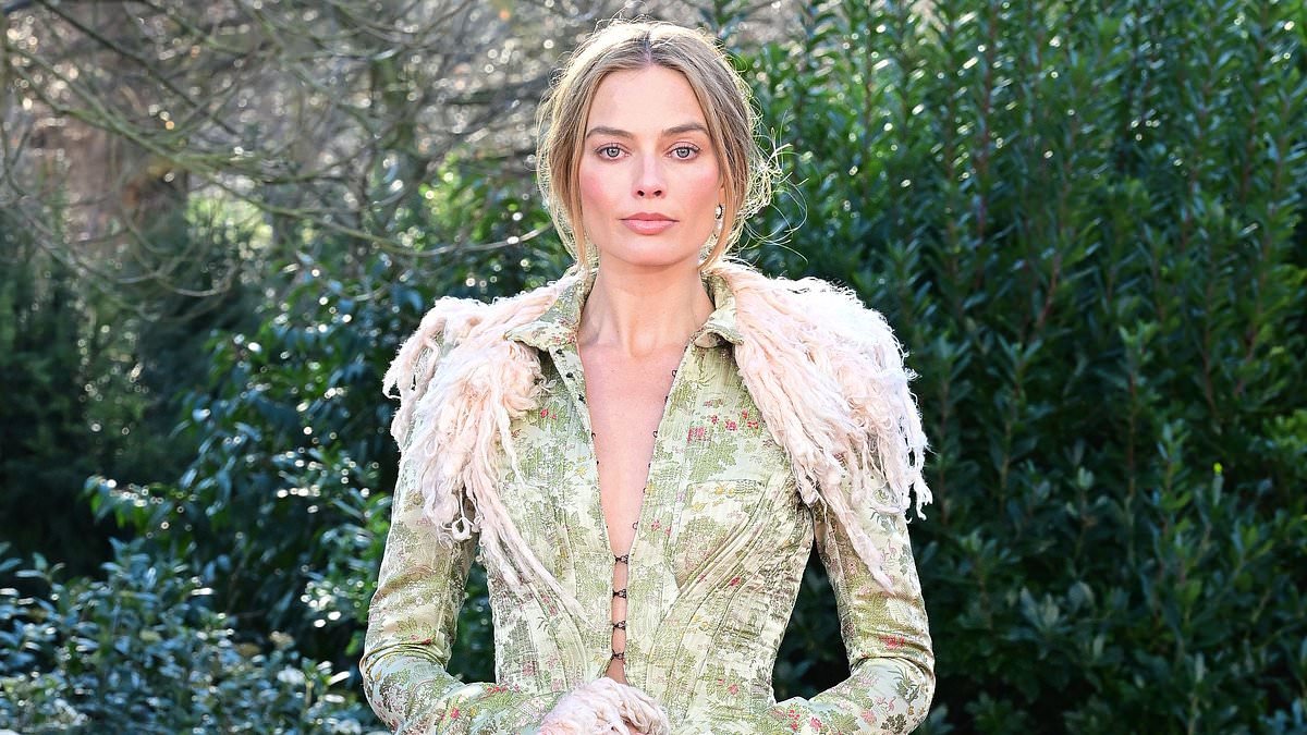 Margot Robbie goes braless in a  plunging period-style coat and stockings as she continues her Wuthering Heights fashion parade during London photocall