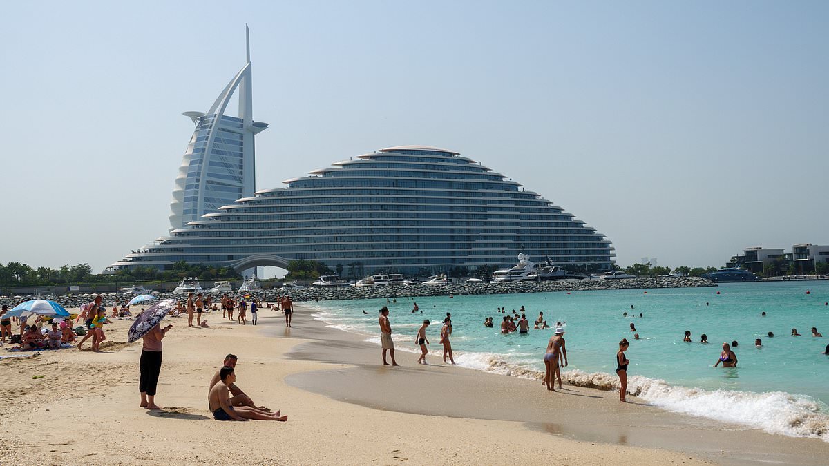 Wish you war here? Tourists and expats enjoy the beach in Dubai in the shadow of hotel smashed by Iranian drone, as conflict continues in the region