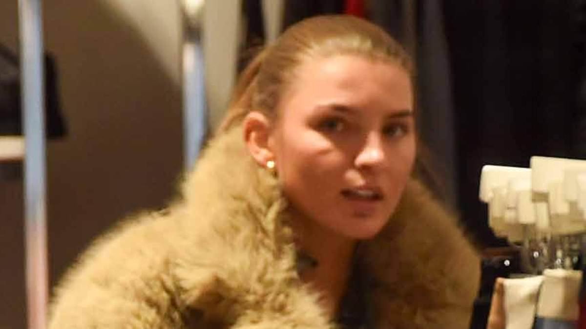 Nepo baby influencer and footballer's step-daughter scrolls on her phone at charity shop after being ordered to do community service for drink-driving