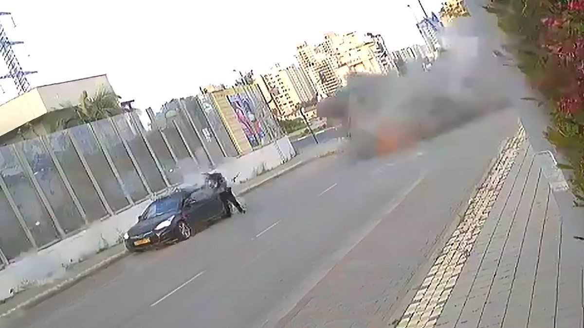 Moment Iran missile lands yards away from Israeli woman, who is knocked to the floor but miraculously manages to walk away