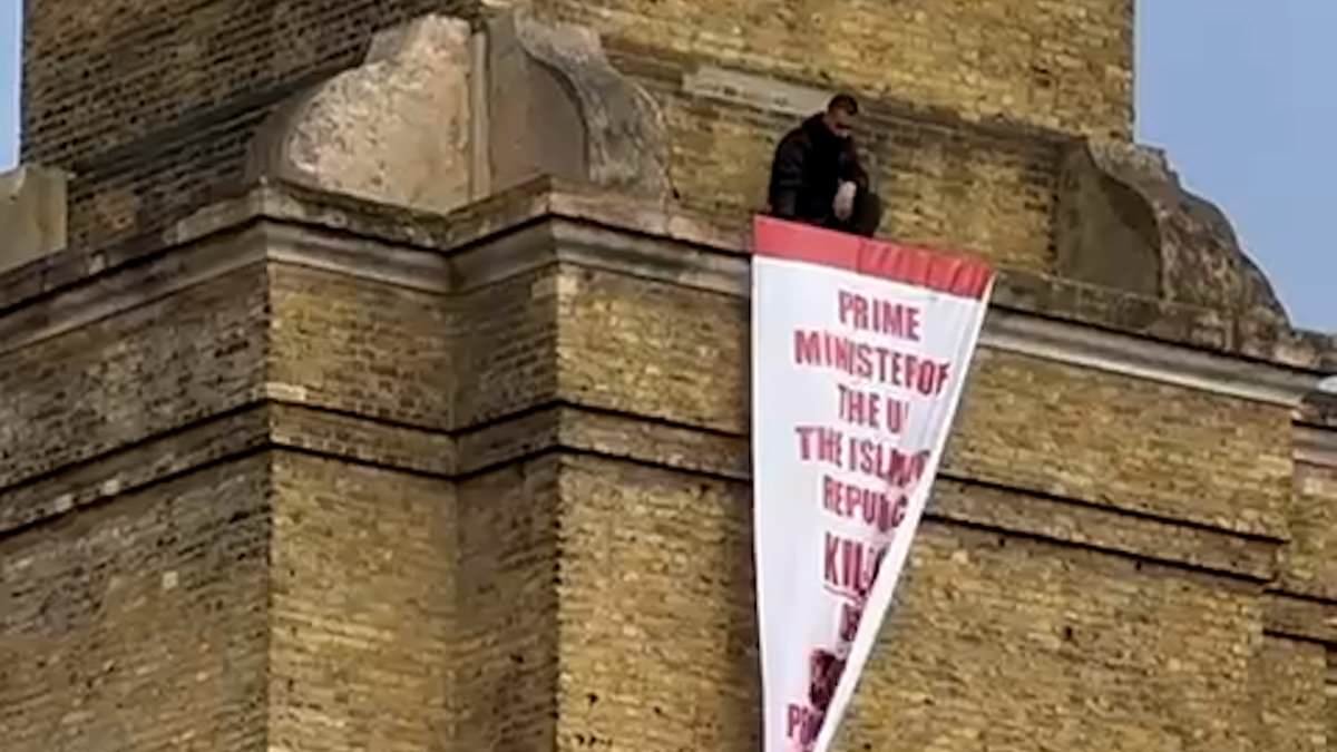 Iran protester scales London's King's Cross station to unfurl banner demanding action from Keir Starmer